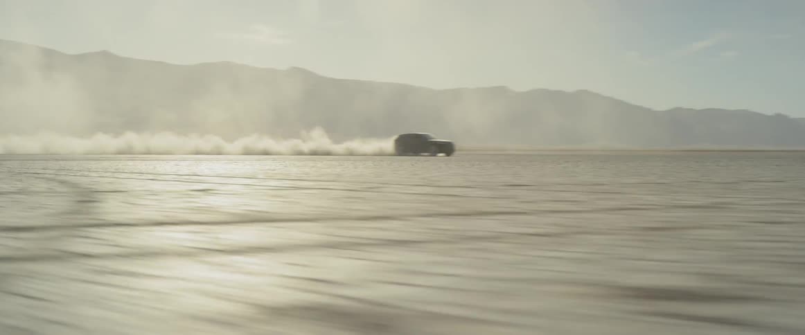 Vehicle driving super fast in the desert in the distance
