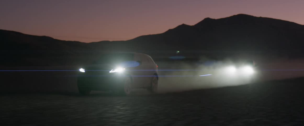 Two range rover sports drive across the desert at night