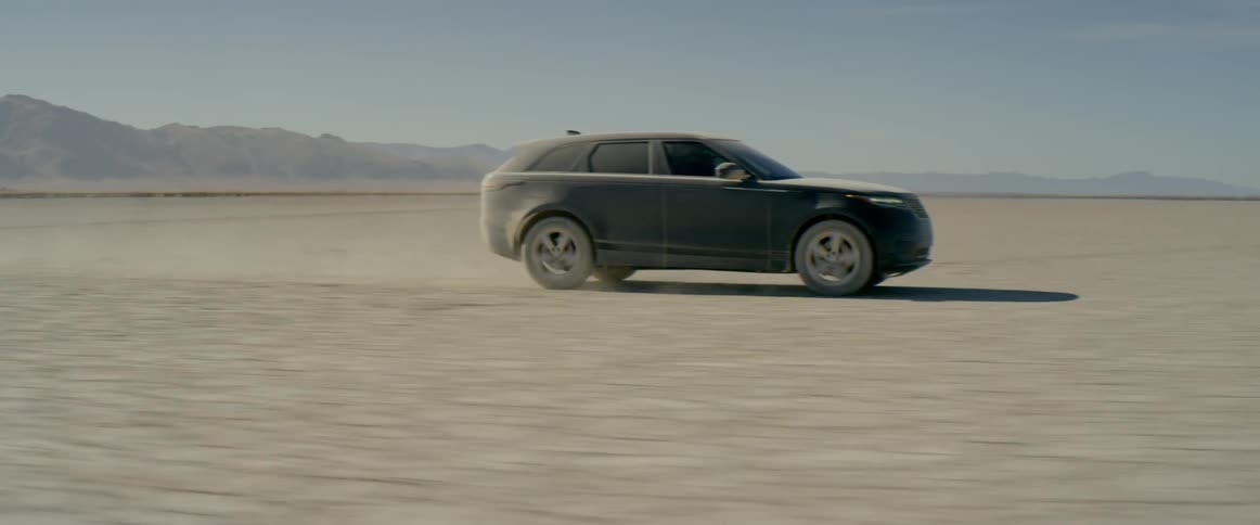 A black range rover sport driving across the salt flats in the afternoon
