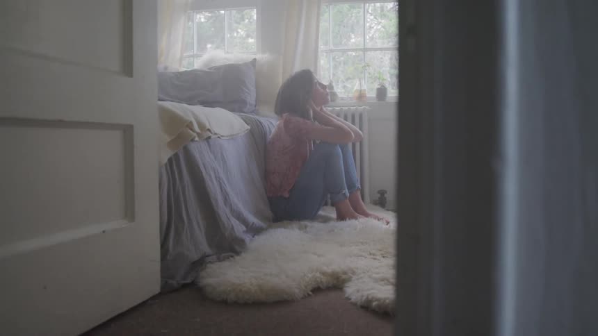 A woman sitting by her bed