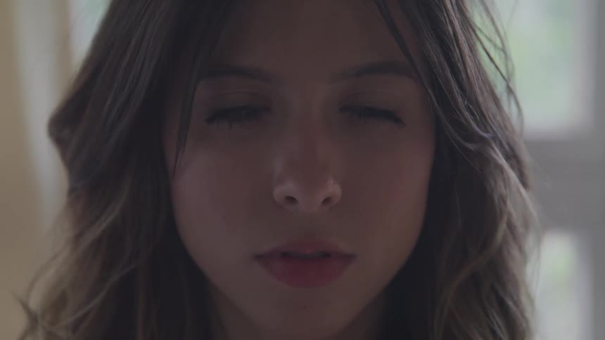 A young woman stares into the camera and blinks