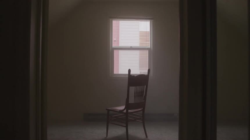 A room with a chair in the middle and a window