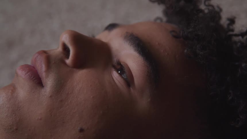 Close up of face of a young man laying on the ground