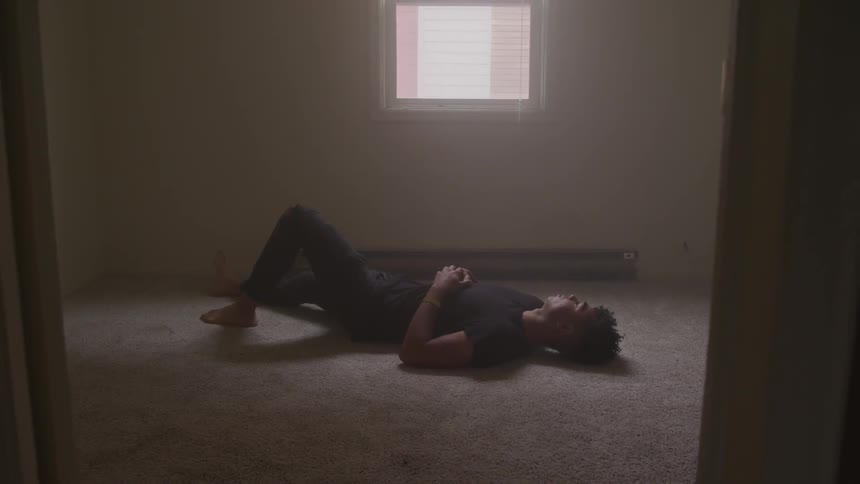 A man lays on the floor in an empty bedroom