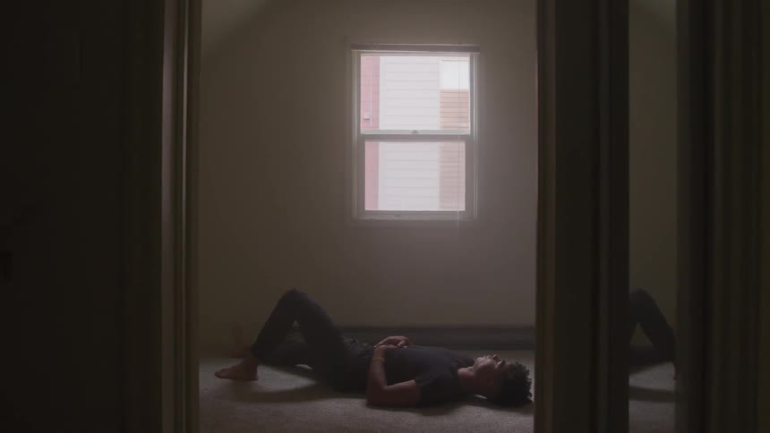 A young man lying on the floor in an empty room
