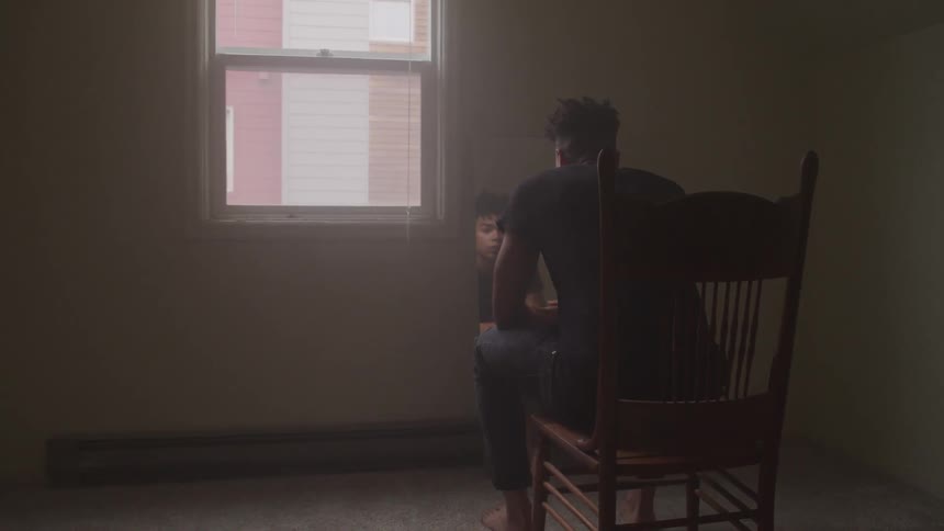 A man sitting down in a chair looking into a mirror