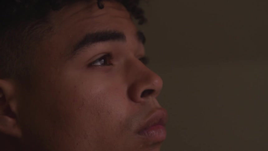 A man with a furrowed brow looks around and blinks