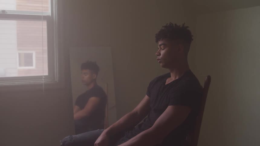 A man sitting in an empty room with a mirror