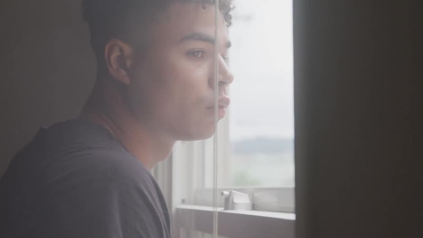 Man in house looks outside through a window
