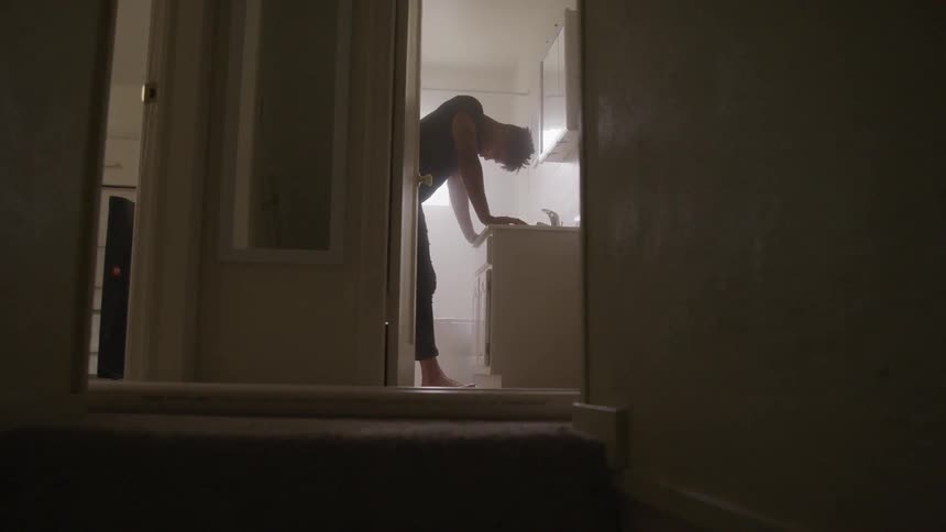 Man stands with head down in the bathroom