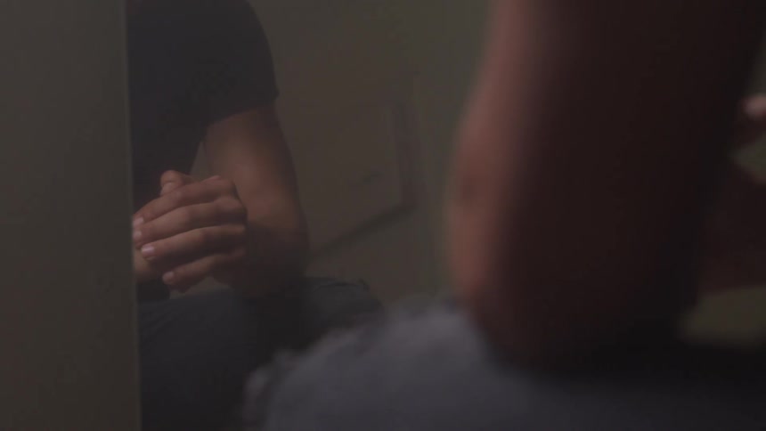 A young man sits in front of a mirror and twists his hands