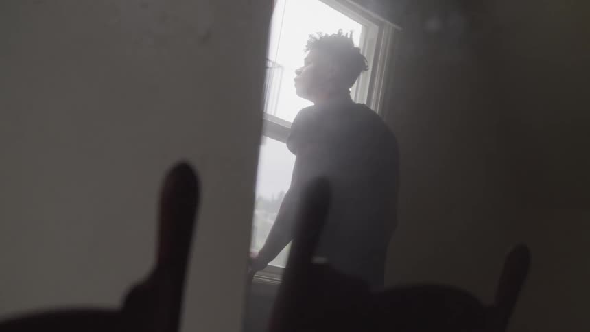 Man inside house standing in front of window looking outside