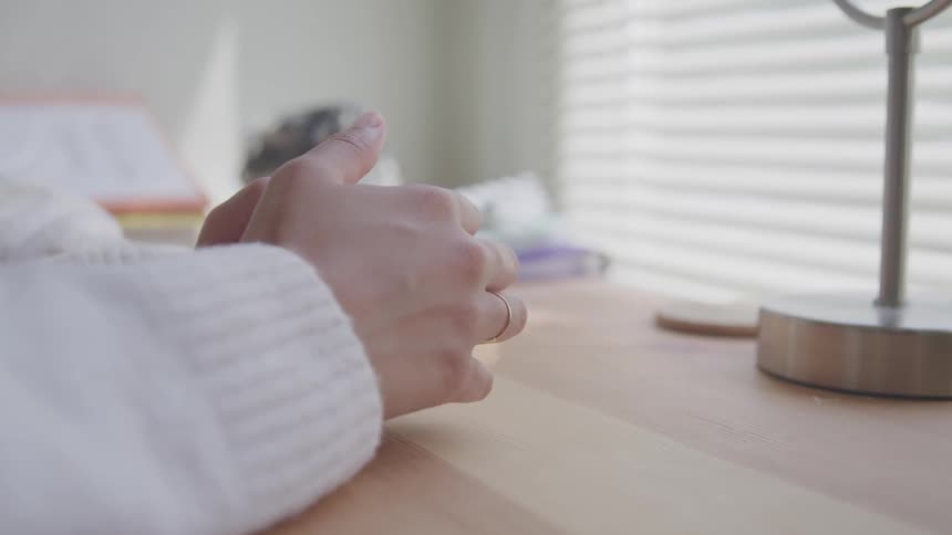 A person sits at a desk and rubs her hands together