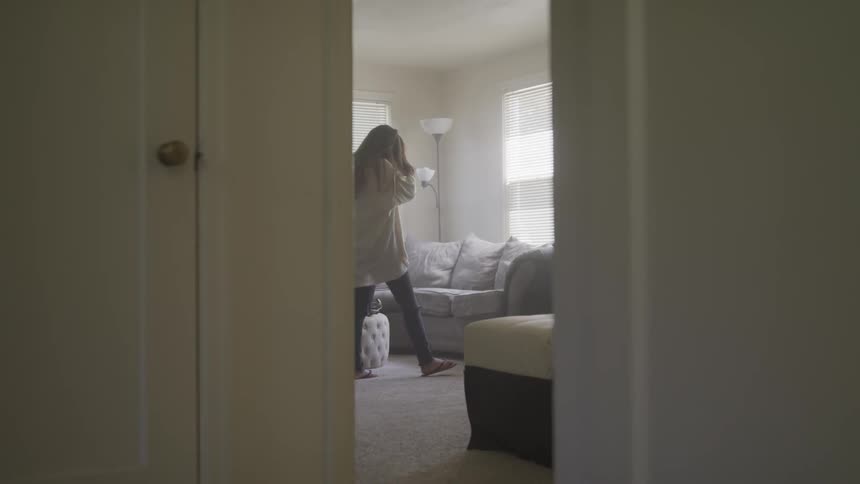 Woman slowly walks back and forth around bedroom