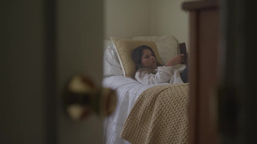 Woman lies on her back on bed reading tablet