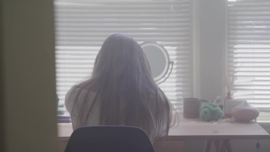 A woman is sitting at the table in the kitchen