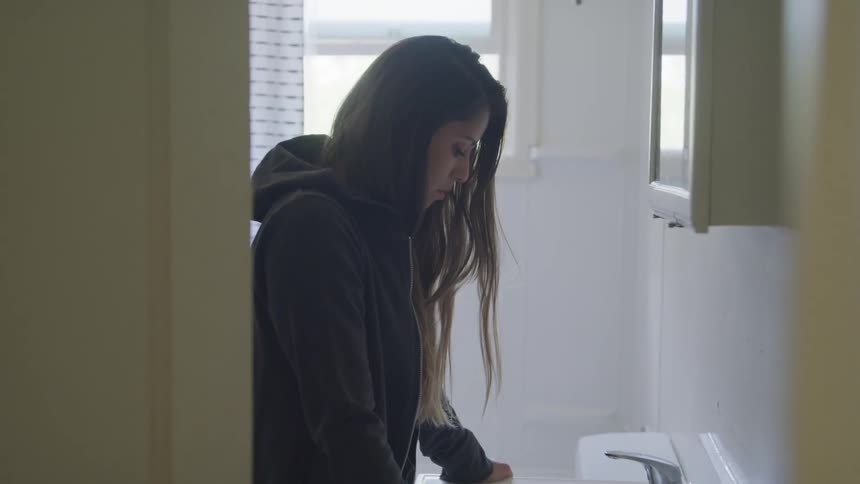 Woman teenager with black hoodie contemplate at the bathroom