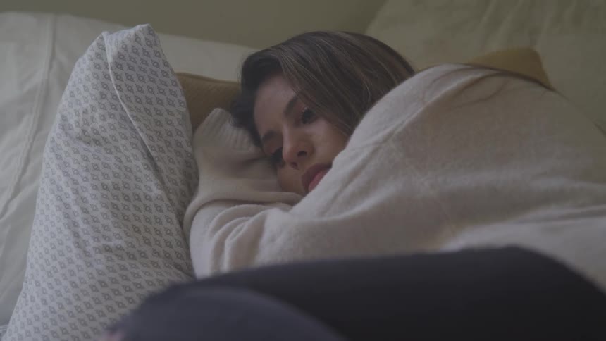 A young woman is lying with her head on a patterned pillow