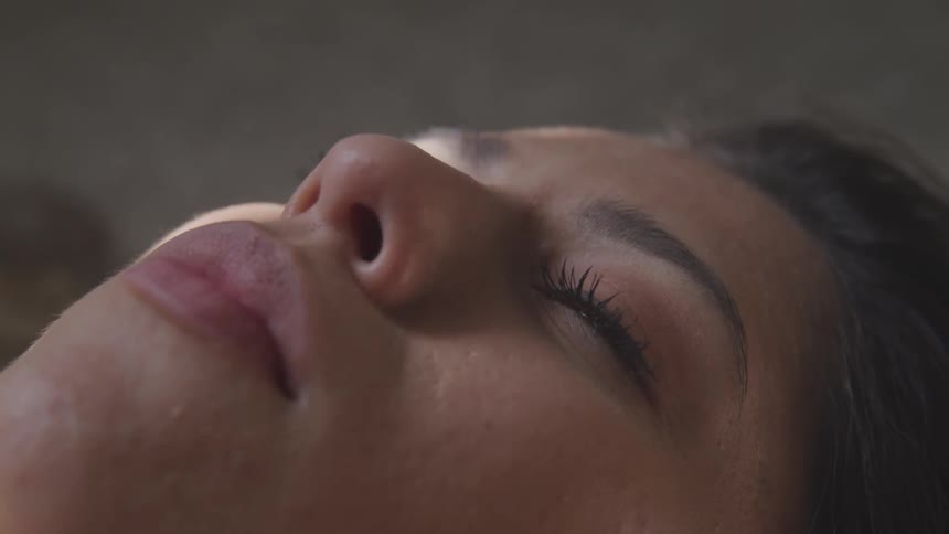 A young woman lies with her eyes closed and then opens them
