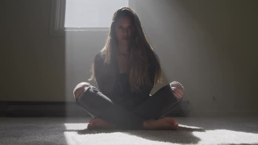 A woman sits on the floor with her legs crossed