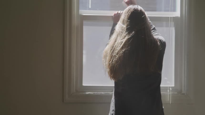 A woman is leaning against the window