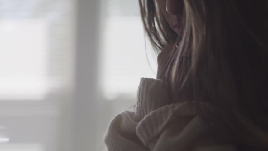 A young girl sits with her head in her hands and looks down