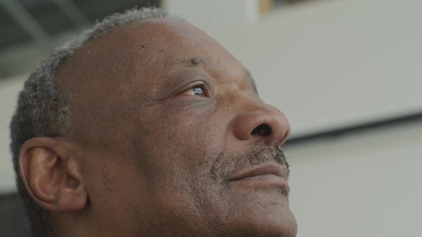 An elderly man stares into the distance