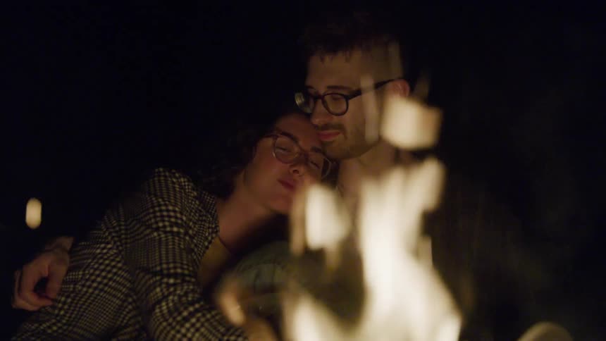 Couple cuddle in front of bonfire at night