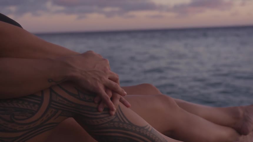 A couple sitting at the beach looking at the dawn