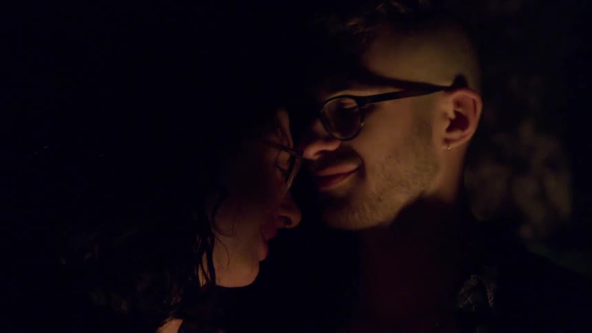 Man and woman dance and kiss each other next to the campfire in the forest at night