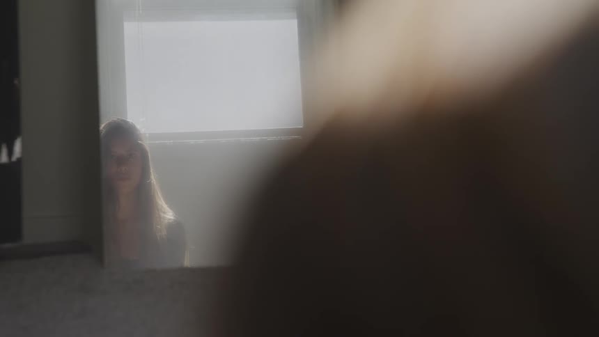 Brunette woman looks at herself in the mirror in a room