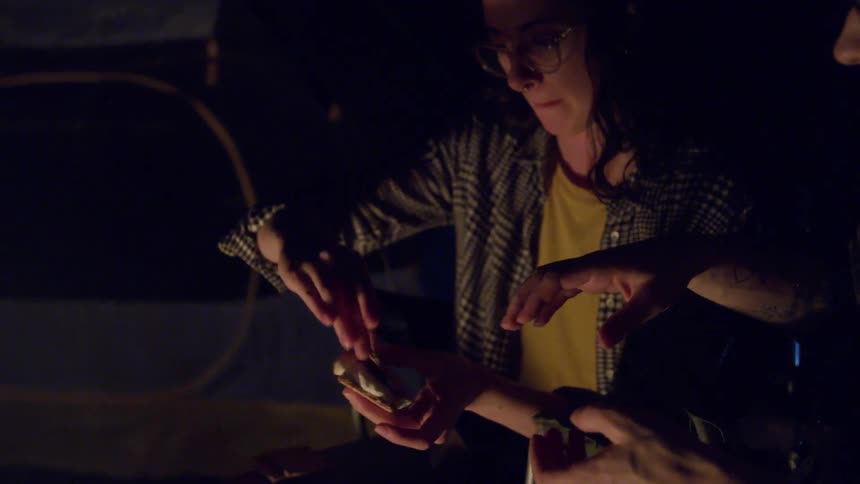 A woman making smores handing it to a man then smiling
