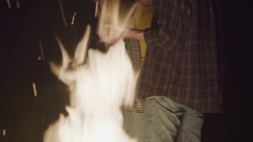 A couple dances by a bonfire