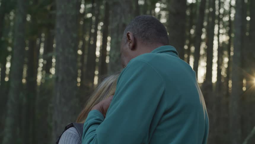Elderly couple hugging on a forest at sunset