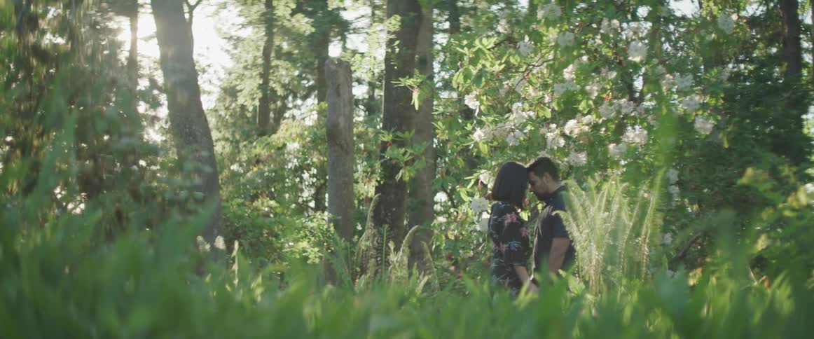 Couple stand close together under flowering tree