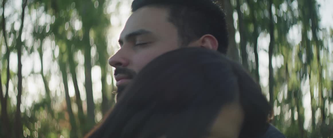 A young man and woman hug outside