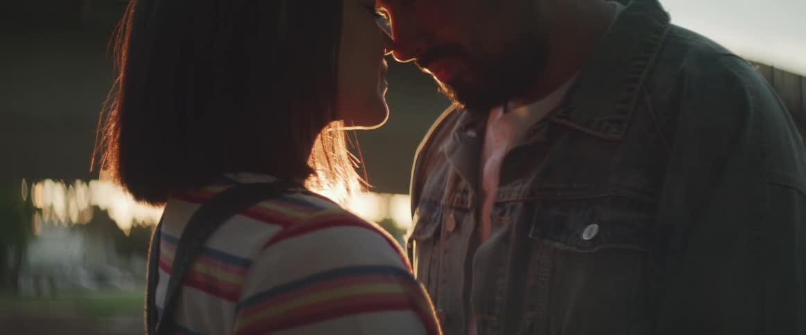 Man and woman hold each other in the public park at sunset
