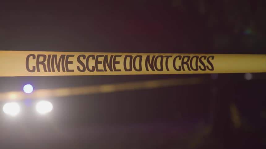Crime scene tape stretches across an area outdoors