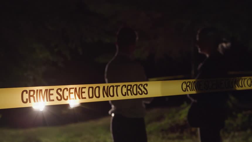 Police officers chat with each other inside a cordoned off crime scene