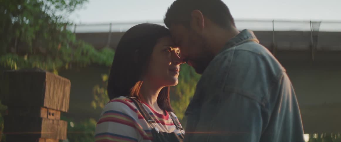 A man and woman lovingly stand together with their foreheads touching