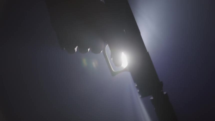 A gun being fired several times in a dark room with a backlight