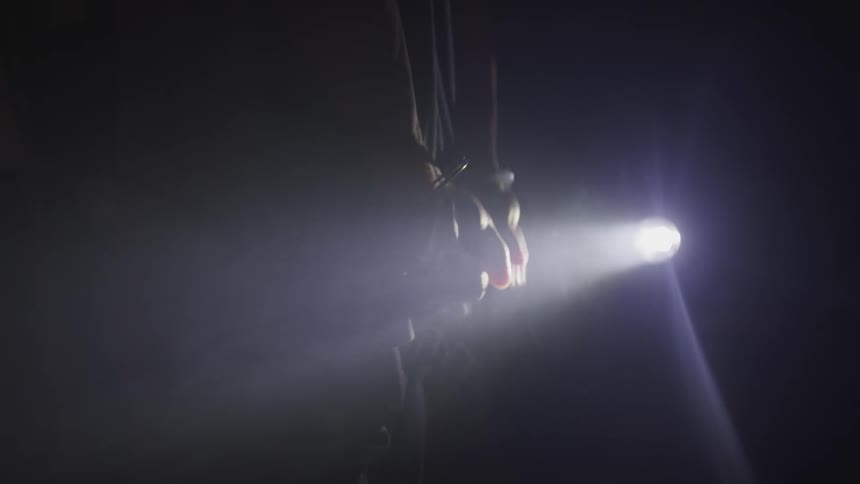 A person in handcuffs in the dark with a light shining on their hands