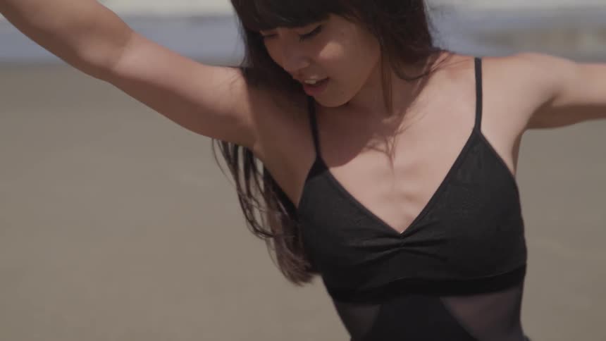 A woman in a black shawl dancing on the beach