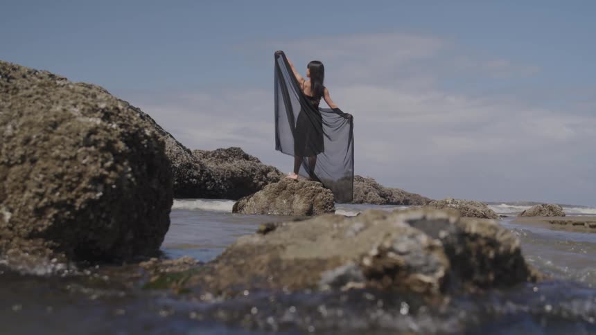 A woman waves her hands near the water