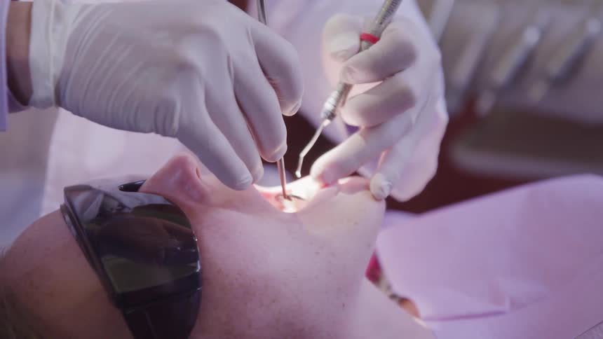A dentist inspects a patients mouth with tools