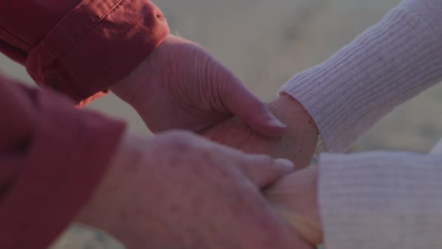 An elderly couple holding hands while standing outdoors