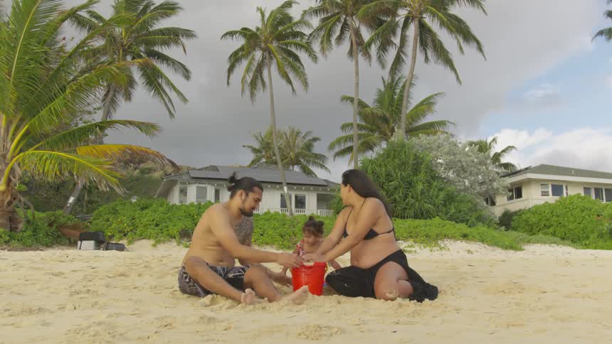 A family packs sand into a bucket at the beach