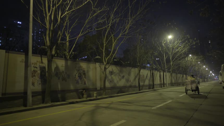 A man drives down a well lit street on a bike