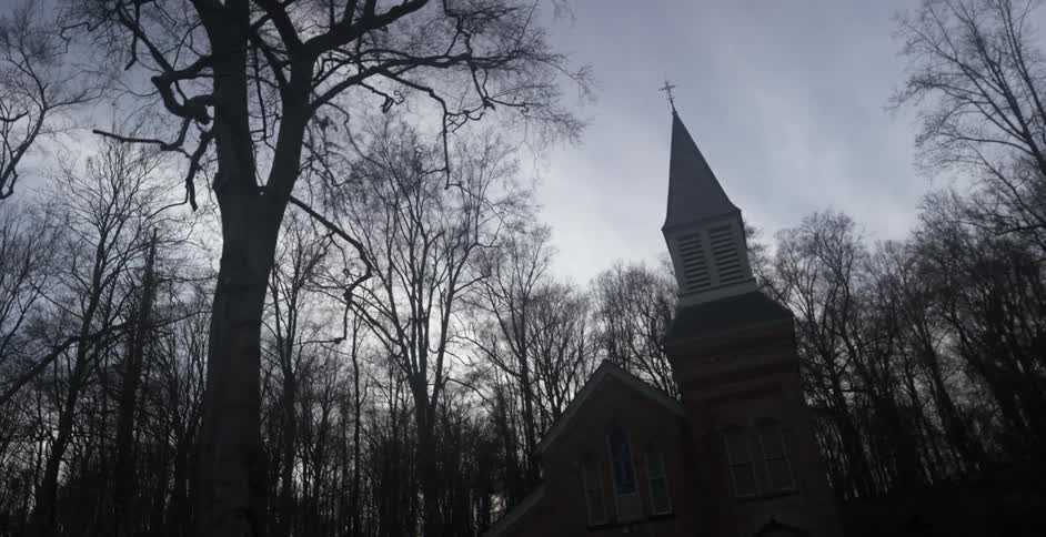 A single building has a cross at the top on a cloudy day