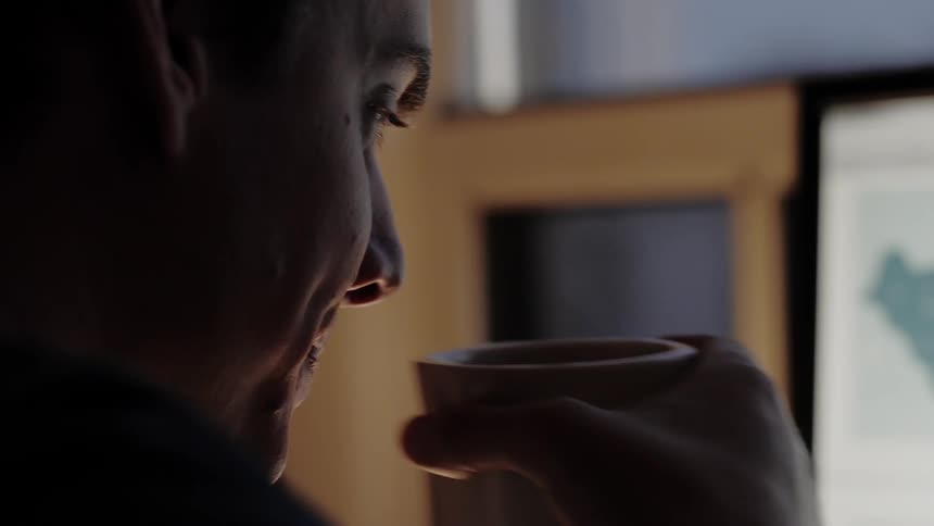 A man drinking out of a coffee cup